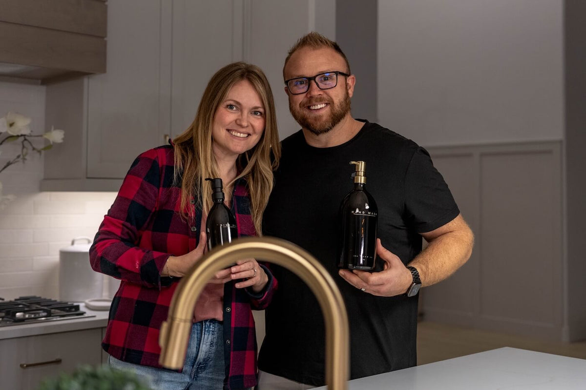 Amber glass hand wash and dish soap bottles with brass pumps beside a brass kitchen faucet